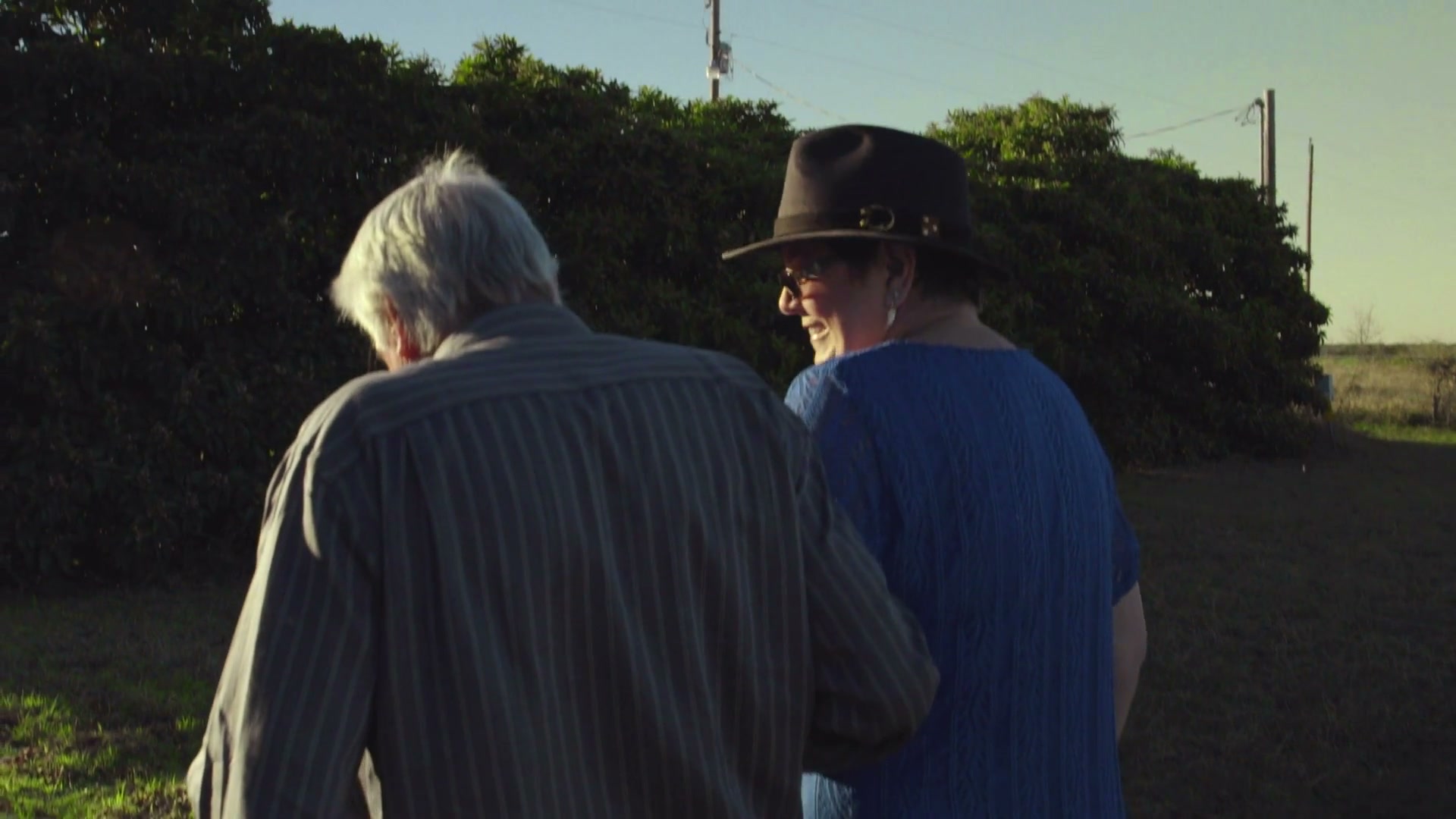 Erin turns and smiles while walking beside another person outdoors.