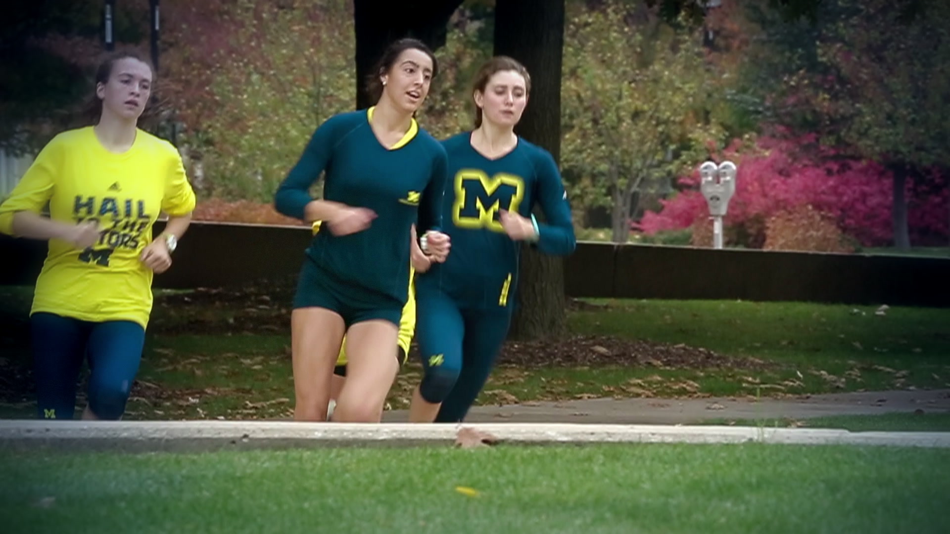 Michigan women’s cross country teammates running together beside the campus